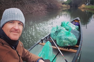 James Elliott (the canoe river cleaner) in his canoe filled with several bags of rubbish picked from the river. 