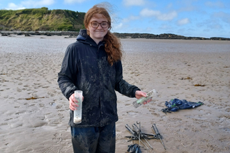 Anna Williams stands on a beach, in waterproof clothing and wellies, during one of her volunteer sessions