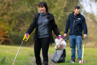 Two volunteers are walking down a path litter picking