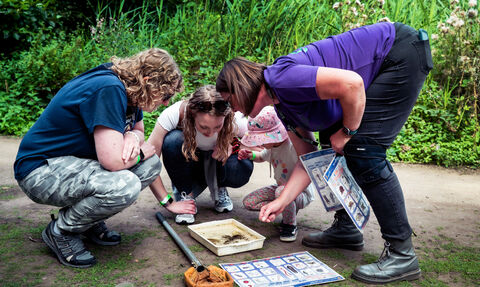 A family examining a tray full of pond creatures