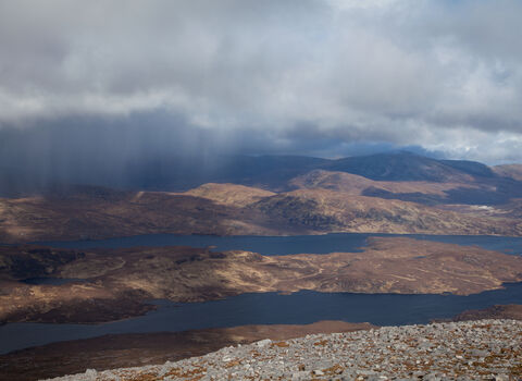 Heavy clouds unleash showers of rain on the rolling hills of the Scottish uplands